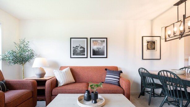 A living room with a sofa, a coffee table, a dining area with chairs, and framed pictures on the wall. - SKI-IN/SKI-OUT 1BDR Condo with Pool & Hot Tub | Spectacular location! (Whistler)