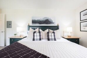 Ein Schlafzimmer mit einem Bett, zwei Nachttischen, einem Kopfteil, einem Wandbild und einer Tür.
