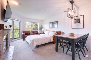 Ein modernes Hotelzimmer mit Bett, Sitzecke, Esstisch und Fernseher.