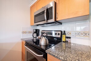 A kitchen with a stainless steel microwave, a kettle, and a coffee maker on the counter. - SKI-IN/SKI-OUT 1BDR Condo with Pool & Hot Tub | Spectacular location! (Whistler)