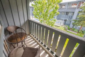 Ein Balkon mit zwei Korbstühlen und Blick auf ein Wohngebäude.