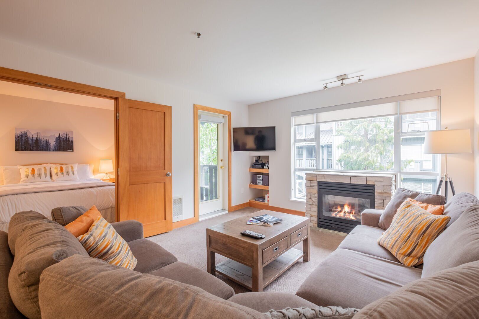 A living room with a fireplace, a sofa set, a coffee table, a TV, and a bookshelf.