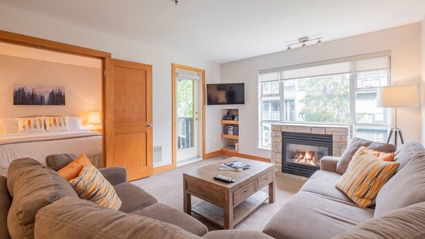Ein Wohnzimmer mit Kamin, einer Sofagarnitur, einem Couchtisch, einem Fernseher und einem Bücherregal.