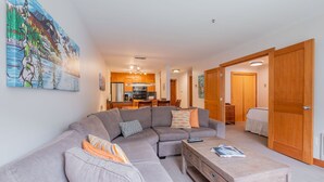 Ein modernes Wohnzimmer mit einer Eckcouch, einem Couchtisch und einer Küche im Hintergrund.