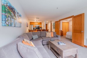 Ein modernes Wohnzimmer mit einer Eckcouch, einem Couchtisch und einer Küche im Hintergrund.