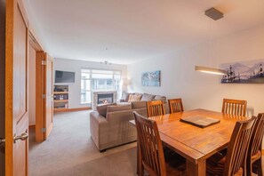 Ein Wohnzimmer mit Sofa, Esstisch mit Stühlen, Kamin und Fernseher.