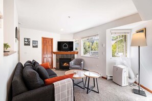 A modern living room with a fireplace, a sofa set, a television, and a lamp. - Cozy Studio in the heart of Whistler | Walk to everything (Whistler)