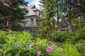 Un panneau en pierre portant les inscriptions « Stoney Creek » et « The Lagoons », une maison avec une façade en pierre et un jardin agrémenté de fleurs roses.