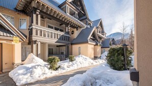 A multi-story building with a snow-covered driveway and a small garden area. - Cozy Studio in the heart of Whistler | Walk to everything (Whistler)
