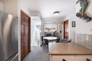 A compact kitchen with a refrigerator, a dining table with chairs, and a small island. - Cozy Studio in the heart of Whistler | Walk to everything (Whistler)