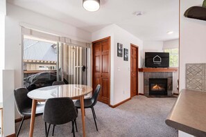 A modern interior with a round glass table, chairs, a fireplace, and a television. - Cozy Studio in the heart of Whistler | Walk to everything (Whistler)