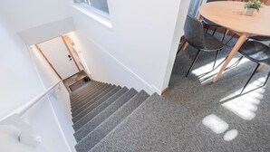 A staircase leading to a room with a dining area, a window, and a door. - Cozy Studio in the heart of Whistler | Walk to everything (Whistler)