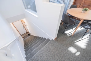 A staircase leading to a room with a dining area, a window, and a door. - Cozy Studio in the heart of Whistler | Walk to everything (Whistler)