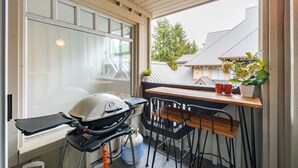 A balcony with a grill, chairs, a table, and a potted plant. - Cozy Studio in the heart of Whistler | Walk to everything (Whistler)