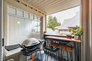 A balcony with a grill, chairs, a table, and a potted plant. - Cozy Studio in the heart of Whistler | Walk to everything (Whistler)