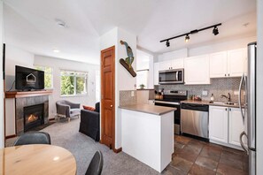 A modern kitchen with white cabinets, a built-in microwave, and stainless steel appliances. - Cozy Studio in the heart of Whistler | Walk to everything (Whistler)