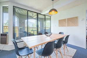 A modern dining area with a wooden table and black chairs, large windows, and a ceiling light. - Mountain views | Pool, hot tub & gym | Ski-in/out (Whistler)