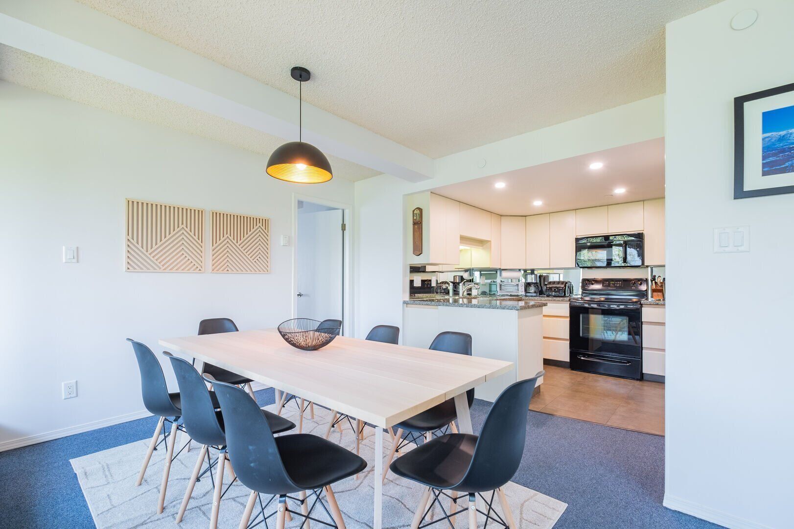 Una cocina moderna con una isla central, electrodomésticos integrados y una zona de comedor con mesa y sillas.