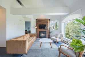 A modern living room with a fireplace, a sofa, a coffee table, and a chair. - Mountain views | Pool, hot tub & gym | Ski-in/out (Whistler)