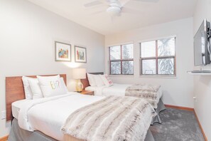 A hotel room with two beds, a ceiling fan, artwork on the wall, and a TV mounted on the wall. - Pool & hot tub | Free parking | Excellent location (Whistler)