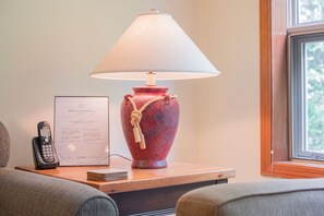 A room with a wooden nightstand, a red vase lamp, a Vtech phone, and a welcome sign. - Ski-in/out apartment | Shared Hot Tub, Pool & Gym | Superb location (Whistler)
