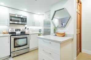 Eine moderne Küche mit Edelstahlgeräten, weißen Schränken und einer Holznäpfchen auf der Arbeitsfläche.