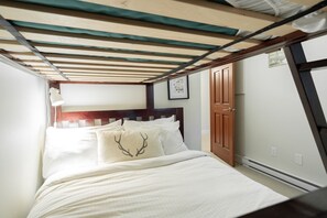 A narrow room with a bed, a door, and a wall-mounted lamp. - Private Hot Tub | BBQ | Free Parking | Location! (Whistler)