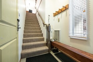 Eine Teppichstufen Treppe mit Handlauf, einer Tierfutterstation und einem Fenster mit Jalousien.