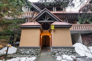 Ein Lodgeneingang mit steinernen Fundament, Holzfassade und einem Balkon mit Geländern.