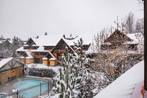 A snow-covered resort with multiple buildings, a swimming pool, and a snowy landscape. - Excellent location | Renovated | Pool & hot tub | BBQ (Whistler)