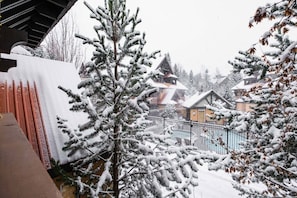 A snow-covered landscape with a building featuring a triangular roof and a pool area. - Excellent location | Renovated | Pool & hot tub | BBQ (Whistler)