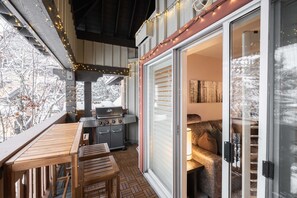 An outdoor patio with a grill, wooden furniture, and string lights. - Excellent location | Renovated | Pool & hot tub | BBQ (Whistler)