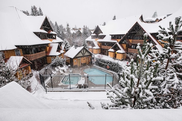 A snow-covered resort with wooden cabins, a swimming pool, and a snowy landscape. - Excellent location | Renovated | Pool & hot tub | BBQ (Whistler)