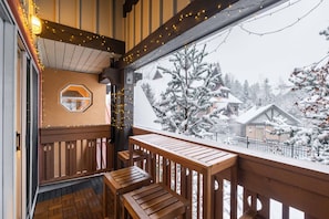 A wooden balcony with a view of snow-covered buildings and trees. - Excellent location | Renovated | Pool & hot tub | BBQ (Whistler)