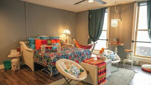 A cozy bedroom with a bed, a chair, a small table, and a hammock.