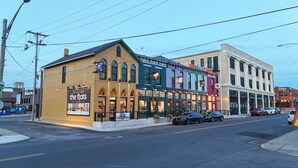A street view with a building featuring a sign for 'the flats' and another building with a colorful sign.
