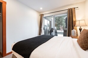 A hotel room with a bed, a window with curtains, a lamp, and a view of the outdoors. - Free parking | Hot tub | Steps to Blackcomb (Whistler)