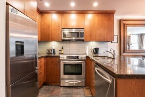 Una cocina moderna con electrodomésticos de acero inoxidable, armarios de madera y un salpicadero de azulejos.