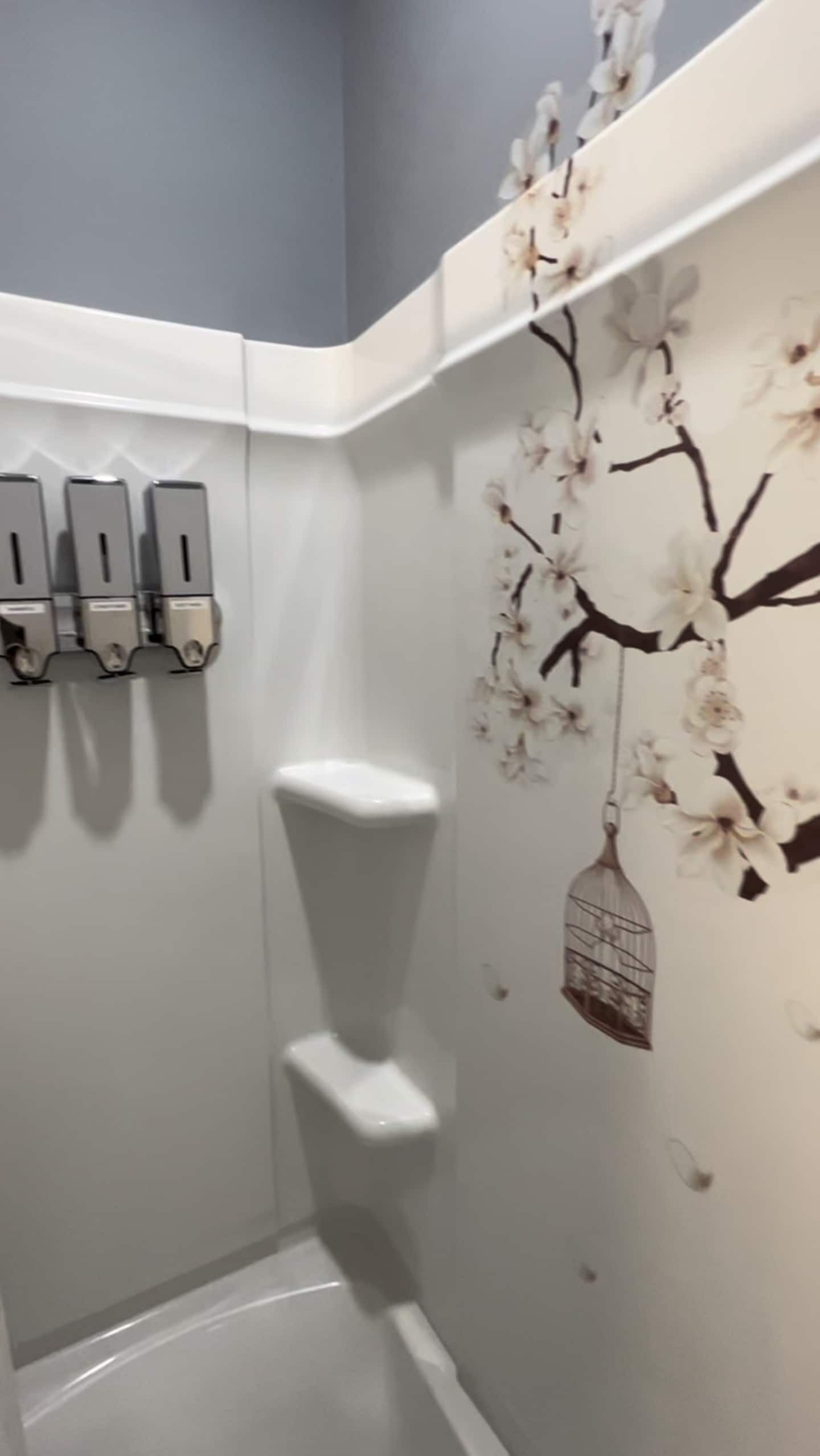 Esquina de un baño con un inodoro, un secamanos y un ambientador de pared.