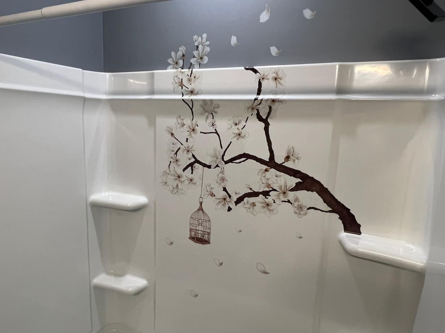 A bathroom with a white sink, a mirror, and a wall with a cherry blossom tree mural.