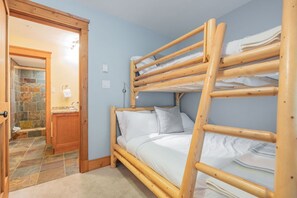 A bunk bed room with a wooden ladder, a bathroom with a stone shower, and a door leading to another room. - Steps to Blackcomb | Free Parking | Hot tub (Whistler)