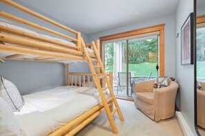 A room with a bunk bed, a ladder, a sofa, and a sliding glass door leading to an outdoor area. - Steps to Blackcomb | Free Parking | Hot tub (Whistler)