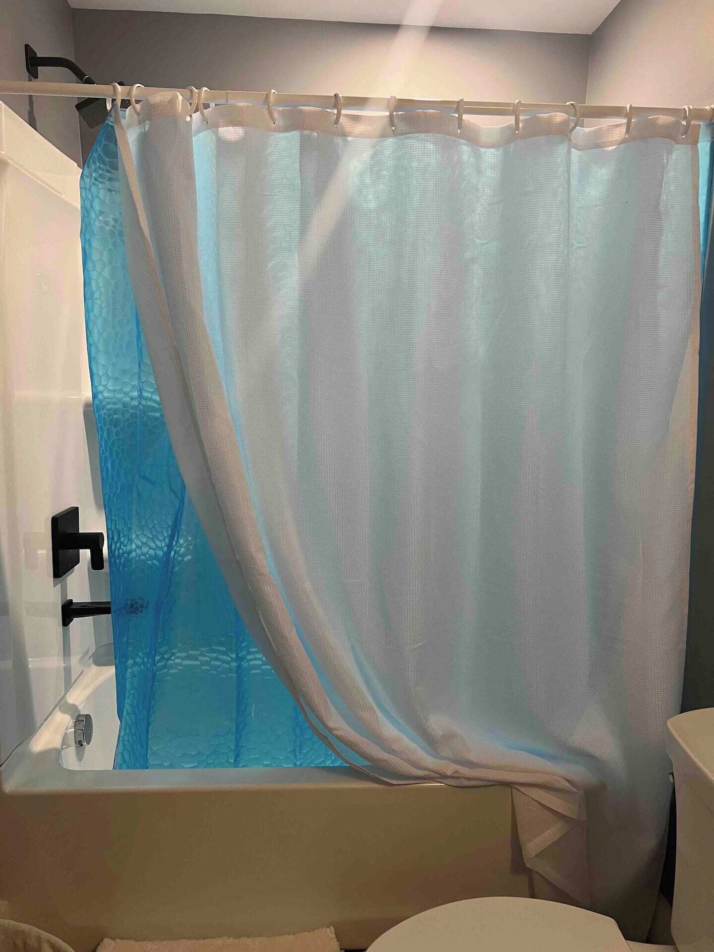 A bathroom with a shower curtain, a bathtub, and a toilet.