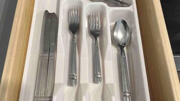 A drawer with compartments containing a knife, fork, spoon, and a set of chopsticks.
