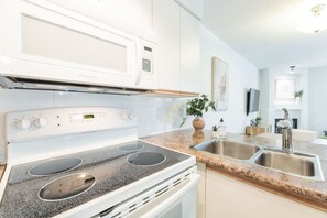 Moderni keittiö, jossa on sisäänrakennettu mikroaaltouuni, liesi ja kaksialtainen tiskiallas.