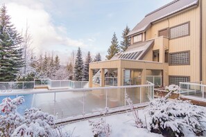 A building with a pool, surrounded by snow-covered trees. - Bright condo | Close to Blackcomb | Free parking (Whistler)