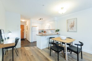 A modern kitchen with white cabinets, a wooden dining table, and black chairs. - Bright condo | Close to Blackcomb | Free parking (Whistler)