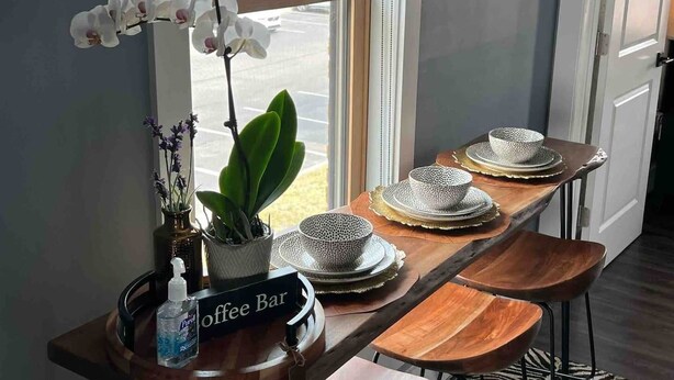 A coffee bar with a sign, a potted plant, and a view of the street through a window. - African Inspired 1BR Flat - Downtown Bellefontaine (Bellefontaine)