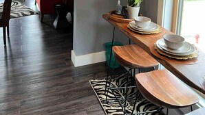 A modern living room with a red sofa, a dining area with wooden tables and chairs, and an air conditioning unit mounted on the wall. - African Inspired 1BR Flat - Downtown Bellefontaine (Bellefontaine)