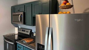A kitchen with a stainless steel refrigerator, a microwave, and a stove. - African Inspired 1BR Flat - Downtown Bellefontaine (Bellefontaine)